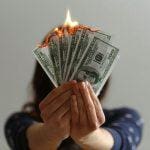 Woman holding burning money symbolizing wasted spending on expensive college consultants