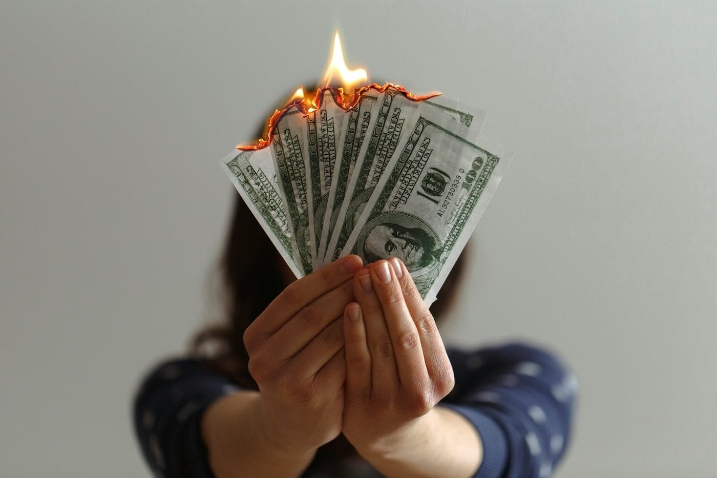 Woman holding burning money symbolizing wasted spending on expensive college consultants