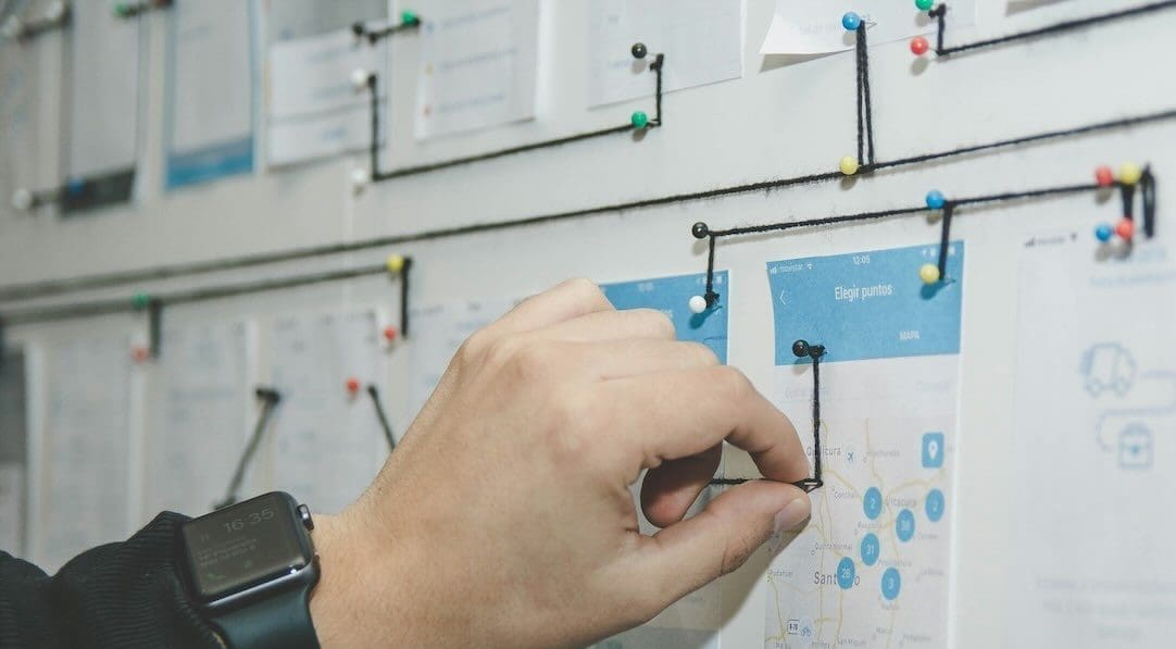 Hand moving pins on a board with levels and symbols, illustrating strategic planning in college admissions and life